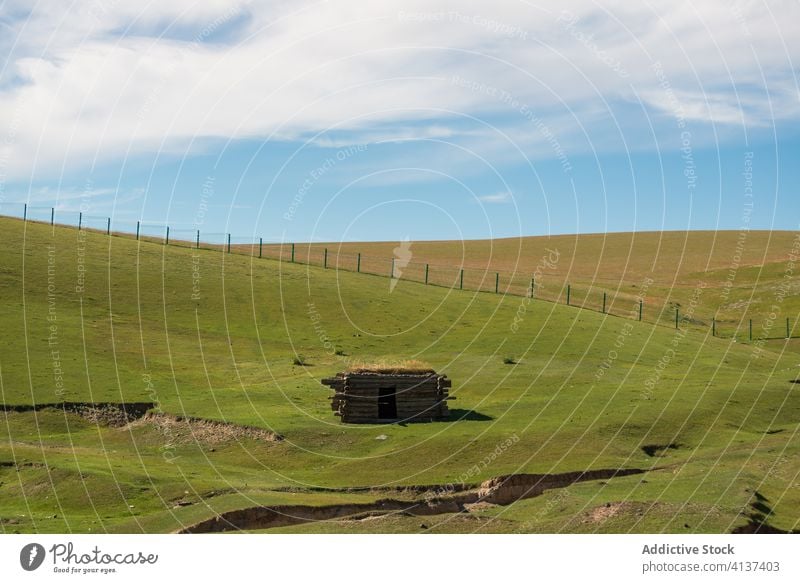 Hölzerne Hütte auf grünem Hügel im Sommer Kabine Landschaft Berghang erstaunlich sonnig grasbewachsen balikun China Natur Haus klein hölzern Zaun friedlich