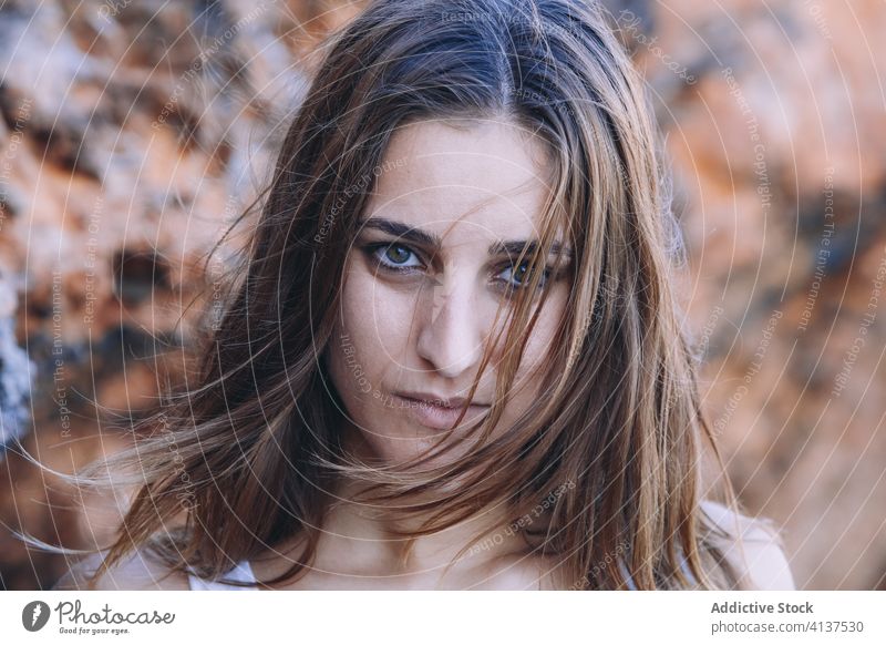 Melancholische Frau in der Nähe eines rauen Felsens traurig Stirnrunzeln Wand Steinwand felsig frustrieren Formation stehen lässig nachdenklich besinnlich ernst