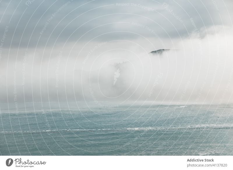 Ruhiges Meer nahe des Hügels unter bewölktem Himmel bei nebligem Wetter MEER Nebel Meereslandschaft Cloud atemberaubend malerisch Natur spektakulär Spanien