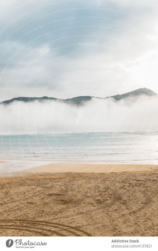 Strand und Meer in der Nähe von Hügeln unter bewölktem Himmel bei nebligem Wetter MEER Nebel Meereslandschaft Cloud atemberaubend malerisch Natur spektakulär