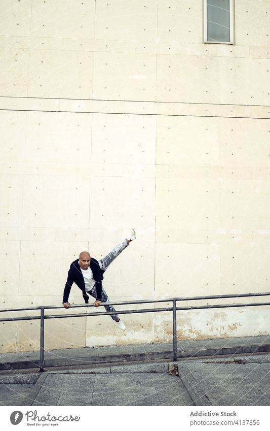 Ethnischer Mann macht Parkour in der Stadt Le Parkour Trick Großstadt springen Reling Straße beweglich Energie urban männlich ethnisch Bewegung Aktion Fähigkeit