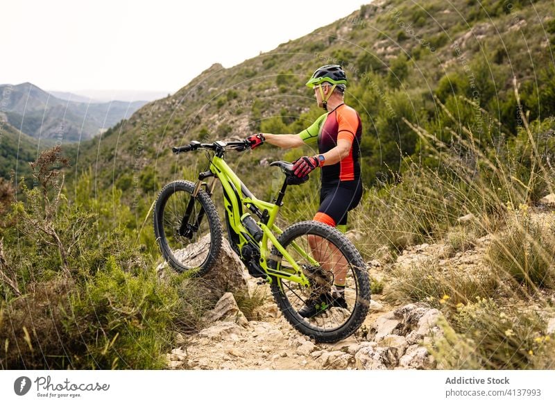 Mann steht neben Mountainbike im Wald Fahrrad Mitfahrgelegenheit Stein Herbst extrem Schutzhelm Sport Natur Adrenalin Lifestyle Landschaft Abenteuer