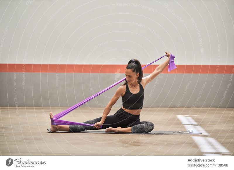 Flexible Sportlerin beim Training mit Gummiband im Fitnessstudio widersetzen Band elastisch Dehnung beweglich Übung Frau heiter Sportkleidung Barfuß Unterlage