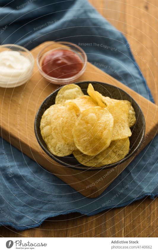 Leckere Kartoffelchips in einer Schüssel auf dem Tisch Chip Knusprig geschmackvoll Schalen & Schüsseln Ketchup Sauerrahm Junk Food Snack lecker Fastfood Saucen