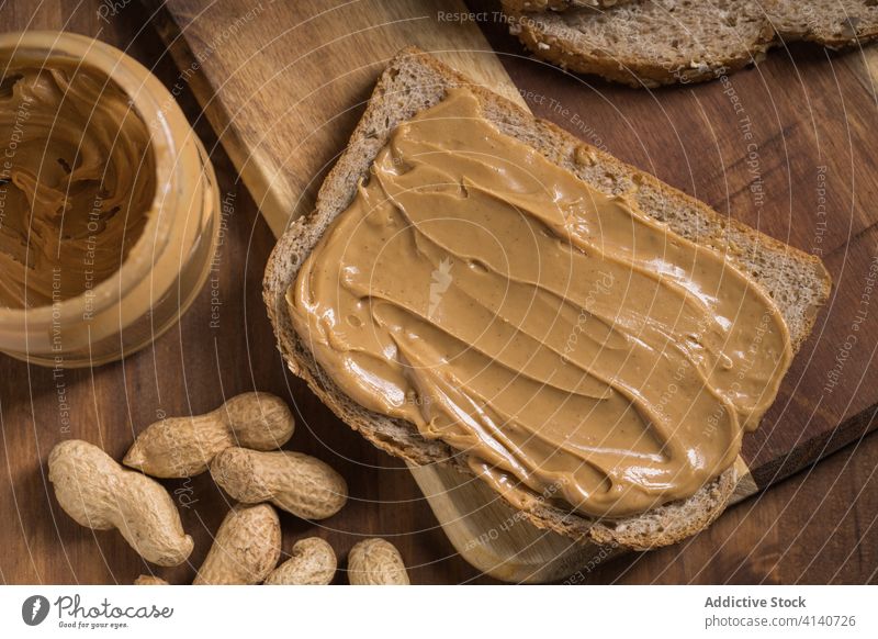 Leckerer Toast mit Erdnussbutter auf Schneidebrett Butter Zuprosten Brot lecker Frühstück Lebensmittel Spielfigur geschmackvoll Ernährung Tisch hölzern Küche