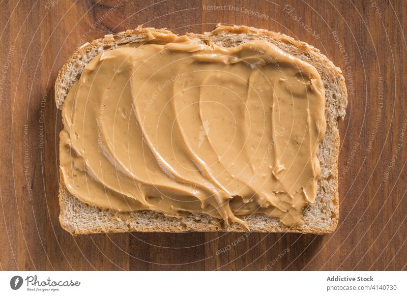 Leckerer Toast mit Erdnussbutter auf Schneidebrett Butter Zuprosten Brot lecker Frühstück Lebensmittel Spielfigur geschmackvoll Ernährung Tisch hölzern Küche