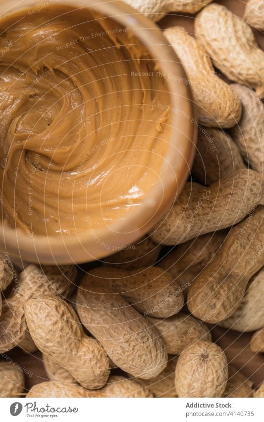 Köstliches Glas mit Erdnussbutter auf Holztisch Butter lecker Frühstück Lebensmittel geschmackvoll Ernährung Tisch hölzern Küche Mahlzeit Gesundheit Morgen