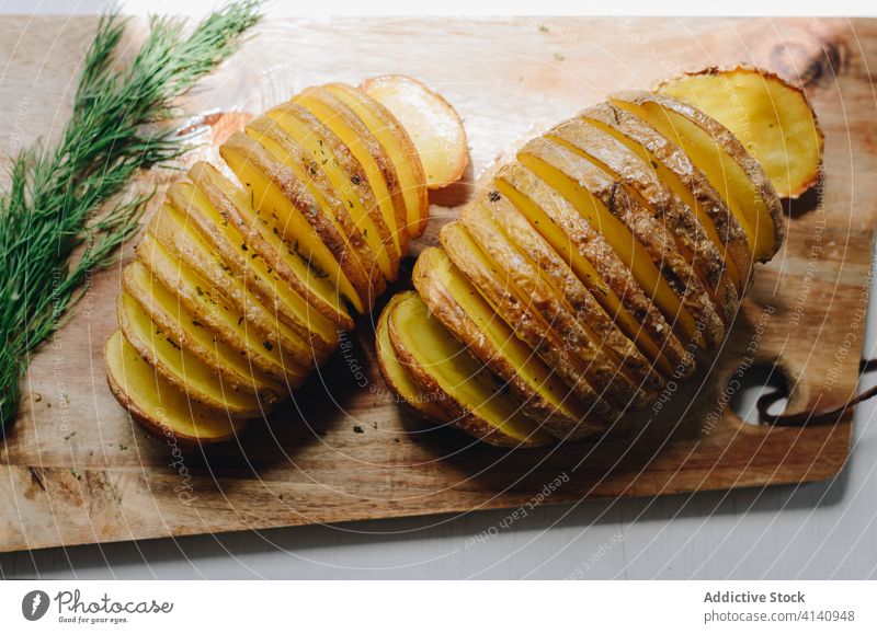 Hasselback-Kartoffeln auf einem hölzernen Schneidebrett in der Küche gebacken dienen Speise Dill lecker Abendessen selbstgemacht geschmackvoll Zweig Mahlzeit