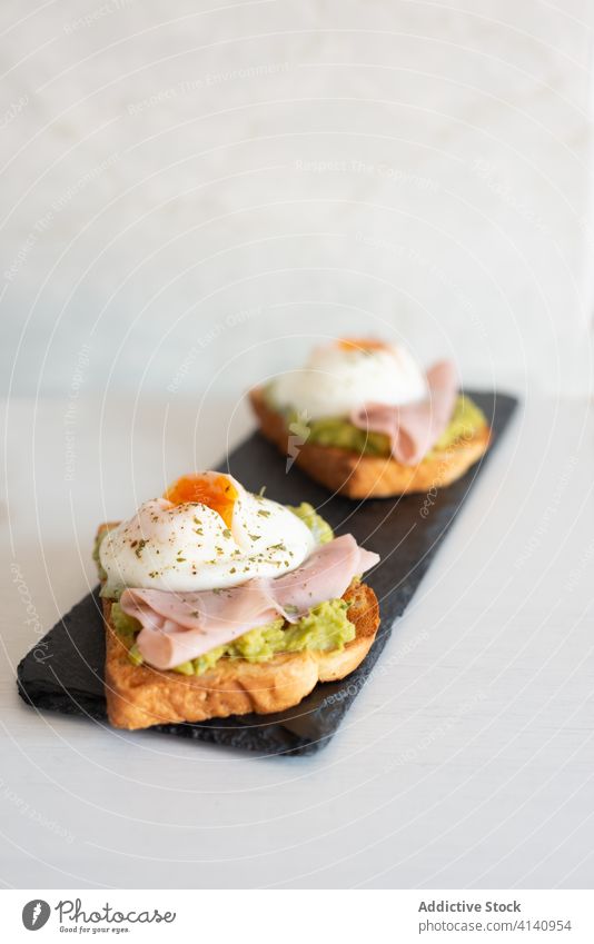 Leckere Toasts mit Spiegeleiern und Schinken Zuprosten Ei gebraten Frühstück geschmackvoll Schiefer Holzplatte Knusprig Küche Guacamole appetitlich