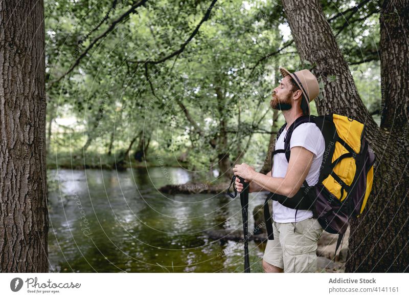 junger Mann auf einem Wanderweg an einem See mit vielen Bäumen und Naturgebieten mit Blick auf die Landschaft wandern reisen Abenteuer Sommer Trekking Tourist