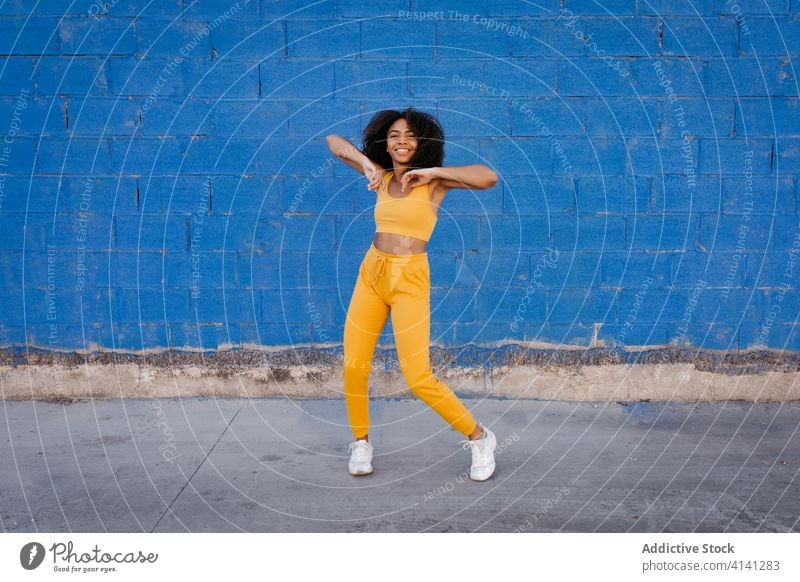 Fröhliche afroamerikanische Frau mit Afro-Frisur in Tanzpose Tanzen Pose sich[Akk] bewegen lebhaft pulsierend heiter Lächeln Bewegung Farbe schwarz ethnisch