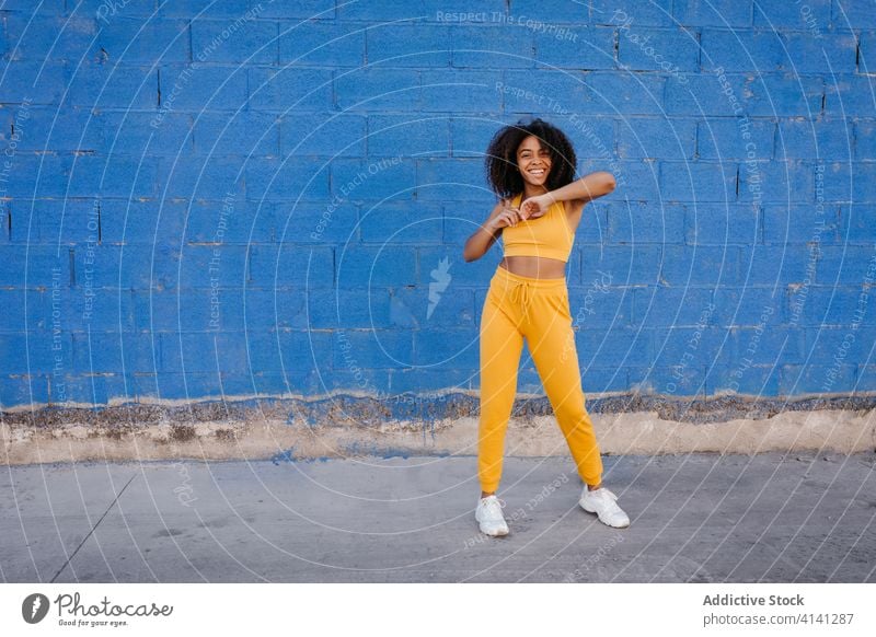 Fröhliche afroamerikanische Frau mit Afro-Frisur in Tanzpose Tanzen Pose sich[Akk] bewegen lebhaft pulsierend heiter Lächeln Bewegung Farbe schwarz ethnisch