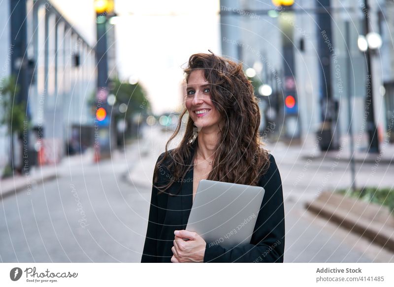 Geschäftsfrau mit Laptop auf der Straße in der Stadt Unternehmer Großstadt selbstbewusst Stadtbild formal gut gekleidet professionell Frau Business heiter