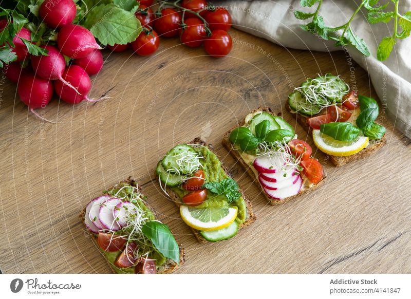 Leckere vegane Toasts mit Tomaten und Gurken auf dem Tisch Veganer Mittagessen Zuprosten Gemüse Vegetarier reif frisch dienen lecker Küche Basilikum Zitrone