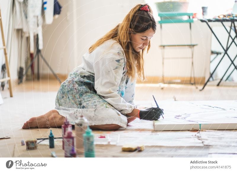 Fröhliche Malerin lacht beim Betrachten eines farbenfrohen Bildes Anstreicher Kunst Lachen Handwerk Talent liquide Barfuß Handschuh Werkstatt Künstler Papier