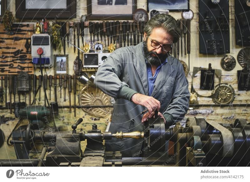 Juwelier mittleren Alters mit Poliermaschine bei der Arbeit im Atelier Goldschmied Polieren Maschine Basteln Metall kleben Prozess Beruf Kleinunternehmen