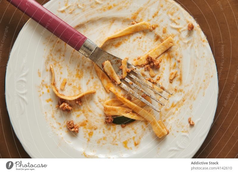 Schmutziger Teller nach dem Essen von Nudeln mit Soße Bolognese Spätzle Saucen Lebensmittel Gabel essen leer Küche kulinarisch dreckig Schliere lecker Mahlzeit