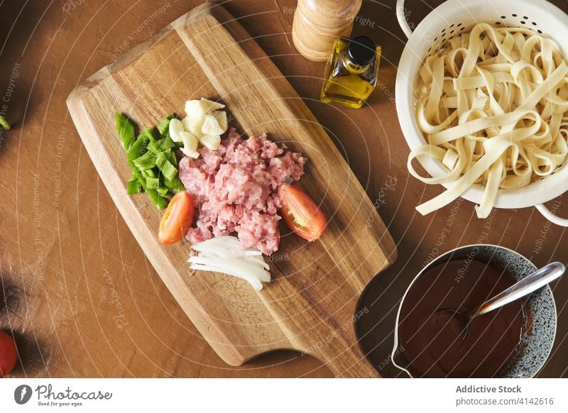 Nudeln und Zutaten für die Sauce auf dem Tisch Bolognese Spätzle Saucen Bestandteil vorbereiten Fleisch Paprika Knoblauch Tomate Zwiebel geschnitten hacken