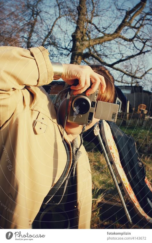 junge Frau beim Fotografieren mit einer analogen Kleinbildkamera analoge fotografie analoge Fotografie fotografierend retro retro-stil knipsen 35mm Fotokamera