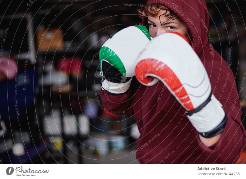 Entschlossene Sportlerin beim Schattenboxen im Fitnessstudio Boxer Boxsport Handschuh Bowle ernst Bestimmen Sie Training Garage stark Konzentration passen