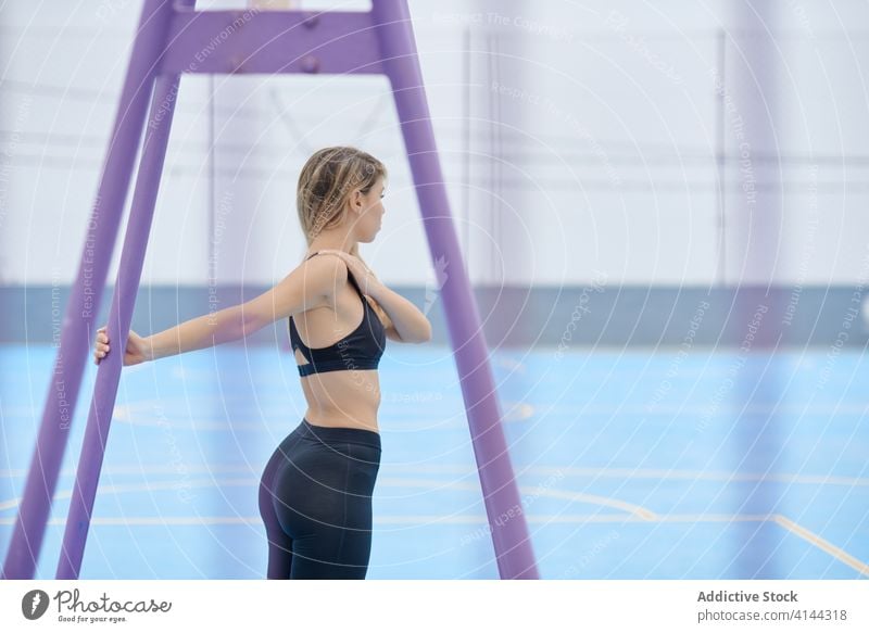 Junge Frau streckt die Arme auf dem Sportplatz Training Übung Dehnung Fitness Athlet schlank Sportlerin Schulter jung modern Wellness Wohlbefinden Gesundheit