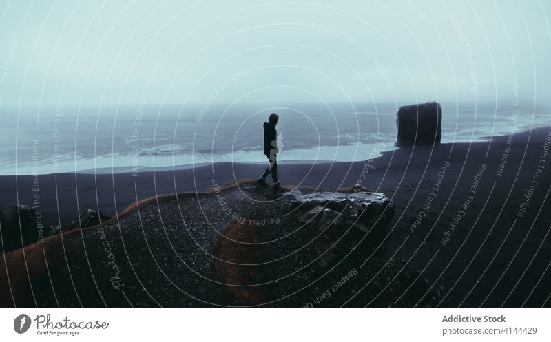 Anonymer Tourist, der sich am Rande einer Klippe oberhalb des Ozeanstrandes erholt Person felsig Strand Meer genießen Reisender Aussichtspunkt Natur Landschaft