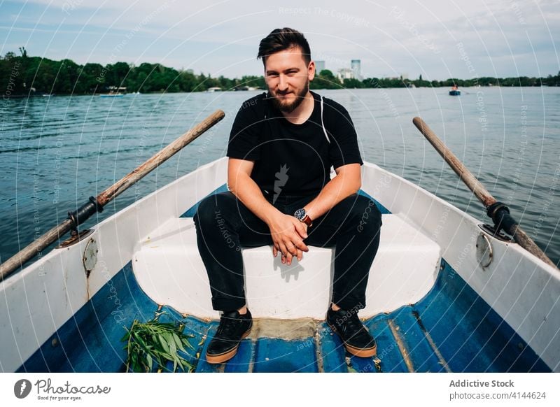 Zufriedener Mann rudert Boot auf friedlichem Teich Rudern See positiv Natur Aktivität Inhalt malerisch Windstille sich[Akk] entspannen Sommer Freizeit