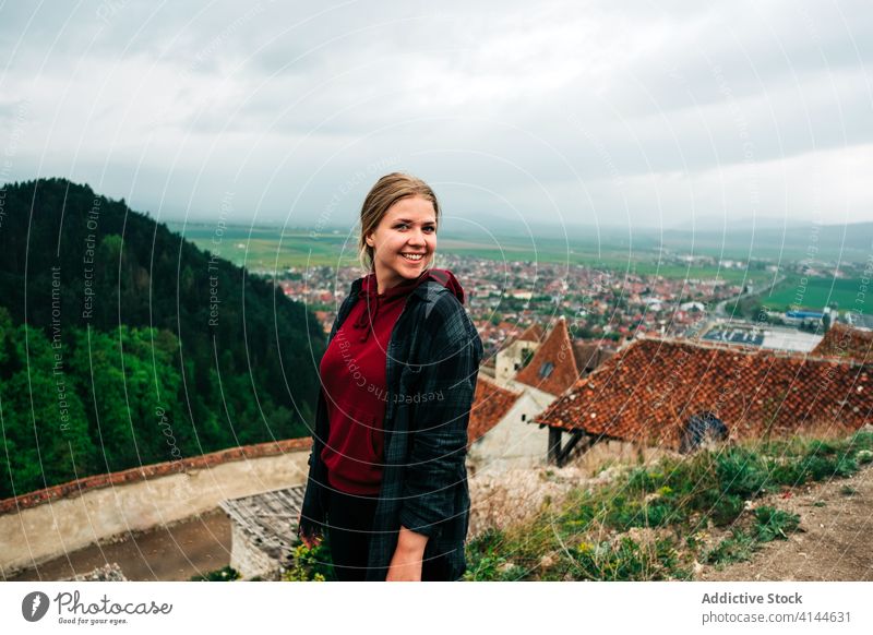 Positive Frau ruht sich auf einem felsigen Aussichtspunkt aus und genießt die Aussicht auf die Stadt Reisender ruhen genießen Landschaft erstaunlich bewundern