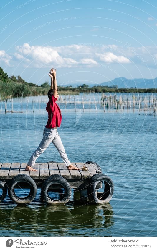 Fiter Mann verbessert Gleichgewicht während er die Natarajasana-Yoga-Pose am Meeresufer macht Herr des Tanzes gyan Mudra Dehnung Pier MEER friedlich üben Asana