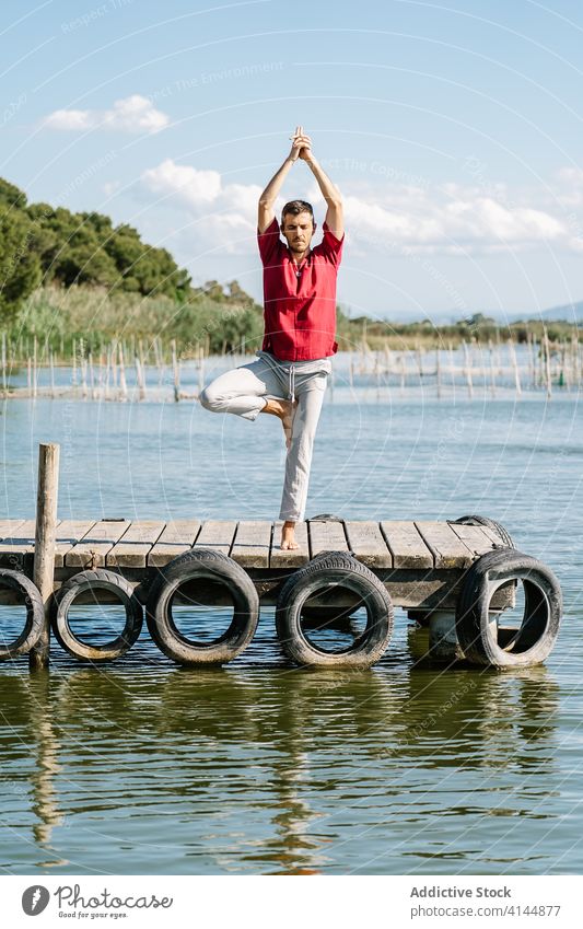 Fiter Mann verbessert Gleichgewicht während er die Natarajasana-Yoga-Pose am Meeresufer macht Herr des Tanzes gyan Mudra Dehnung Pier MEER friedlich üben Asana