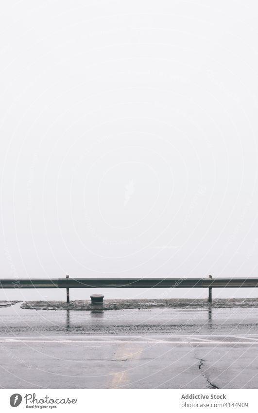 Nasse Asphaltstraße in einer nebligen Stadt nass Straße Nebel Morgen Großstadt leer Fahrbahn trist Metall Zaun verwittert Dunst Wetter erstaunlich ruhig