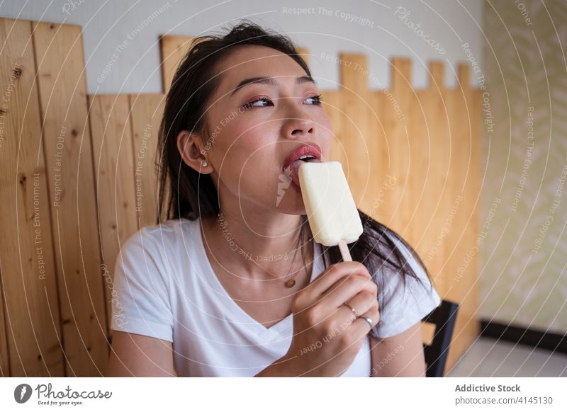 Asiatische Frau isst Eiscreme Speiseeis essen süß Café Tisch sitzen Biss ruhen Wochenende ethnisch asiatisch Dessert lecker geschmackvoll Lebensmittel Freude