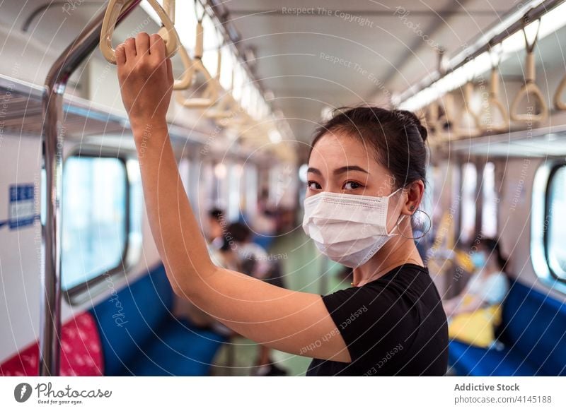 Asiatische Frau in Maske im Zug reisen Mundschutz Coronavirus Öffentlich Verkehr Ausbruch behüten Arbeitsweg ethnisch asiatisch modern Passagier stehen Ausflug