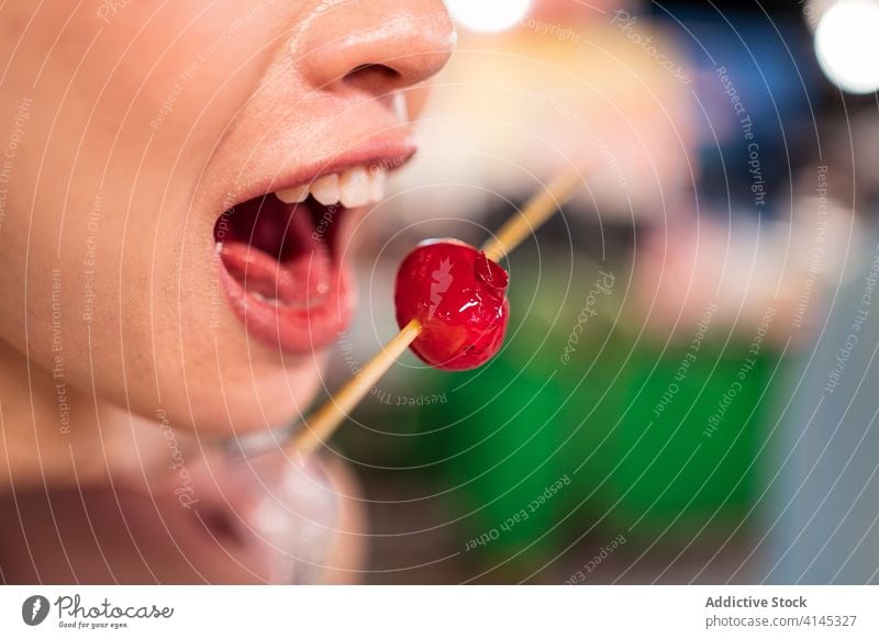 Anonyme Frau isst süße Tomate in der Stadt Nacht Markt Straßenessen Beeren Kirsche Zucker Mantel zhubei Taiwan hölzern kleben geschmackvoll Lebensmittel