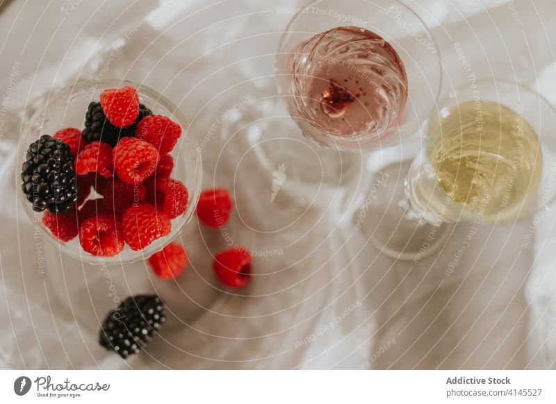 Glas Cocktail mit Beeren und Gläsern, serviert auf einem Tisch vor weißer Wand Flasche Teller trinken Zusammensetzung dienen Dekoration & Verzierung Design