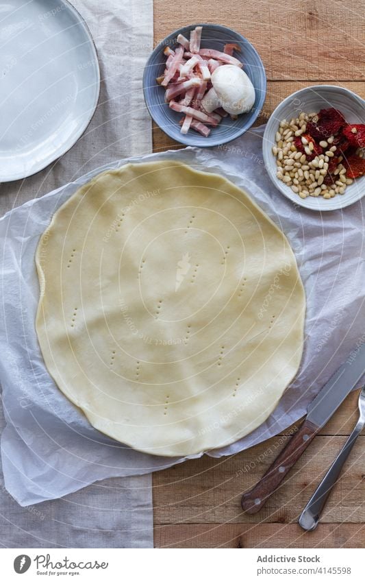 Mit einer Gabel eingestochener Blätterteig neben Schalen mit frischen Zutaten Hauch Gebäck Speisekarte Rezept Bestandteil Mittagessen Pergament kulinarisch