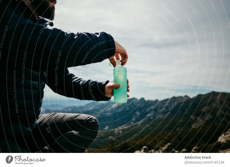 Anonymer männlicher Reisender, der in den Bergen Wasser trinkt Mann Lächeln trinken Berge u. Gebirge ruhen Felsbrocken puerto de la morcuera Spanien heiter