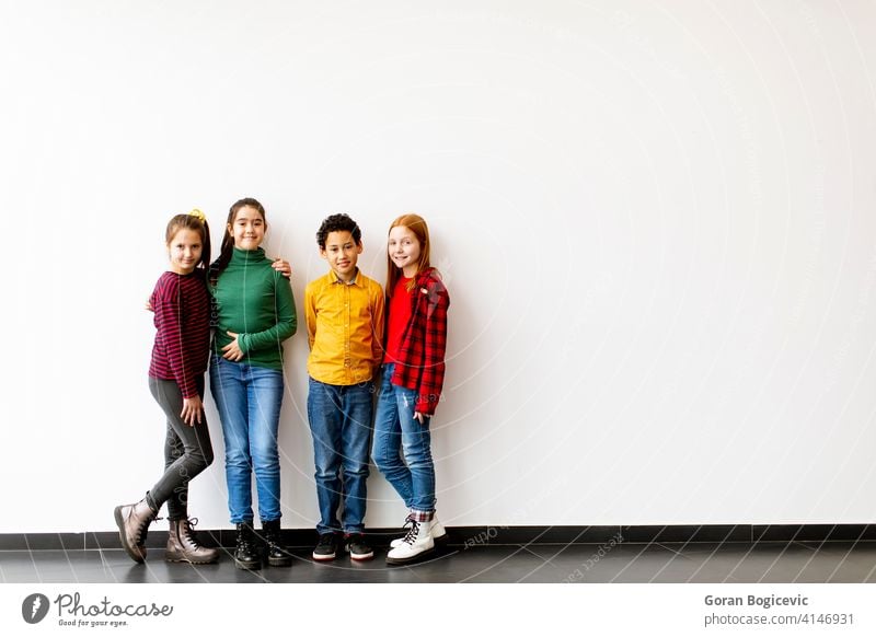 Porträt der niedlichen kleinen Kinder in Jeans Blick auf die Kamera und lächelnd, stehen gegen weiße Wand Kaukasier Junge Schule Mädchen Frau Kindheit männlich