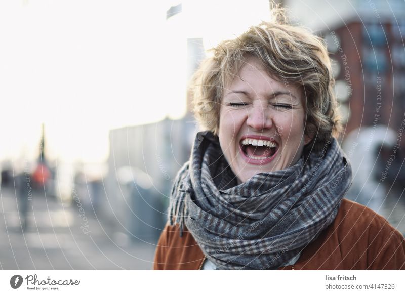 LACHEN Frau blond Locken kurzhaarig Kurzhaarschnitt Schal Augen geschlossen lachen Spaß haben Freude Spaßvogel glücklich ausgelassen Ausgelassenheit