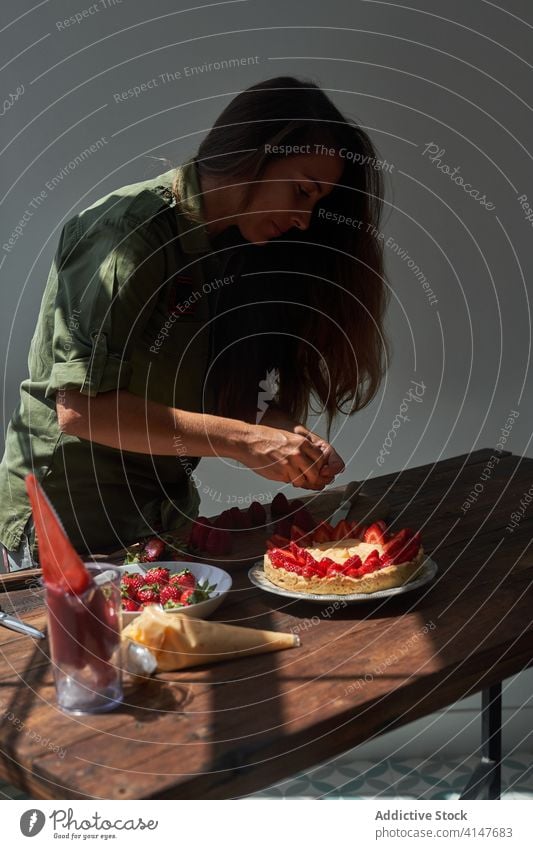 Frau dekoriert Kuchen mit Erdbeeren Pasteten dekorierend Koch Konditorei selbstgemacht lecker Tisch Lebensmittel schmackhaft heimwärts süß Leckerbissen Dessert