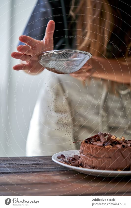 Frau dekoriert Kuchen mit Kakaopulver Hände Konditorei Käsekuchen bestäuben Körperteil Pulver Sieb Dessert Küche gebacken Stil Koch Lebensmittel süß