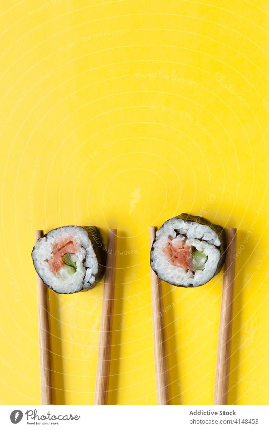 Appetitliche Brötchen und Stäbchen auf gelbem Hintergrund rollen Sushi Essstäbchen Atelier Lachs Reis lecker Asiatische Küche geschmackvoll Tradition