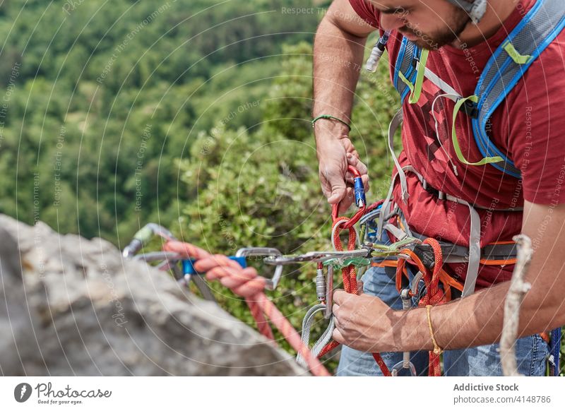 Männlicher Bergsteiger am Seil hängend Alpinist Mann Karabiner ausrichten Kabelbaum Sicherheit Felsen Berge u. Gebirge männlich Abenteuer Aufstieg behüten