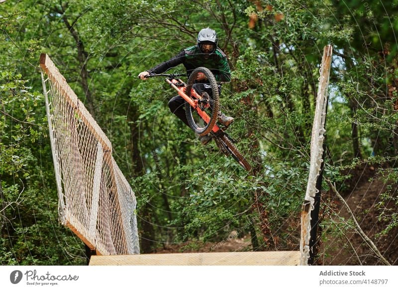 Starker Mann fährt Fahrrad im Wald bergab Trick Stunt extrem Mitfahrgelegenheit Radfahrer Risiko Schutzhelm männlich ausführen professionell Wälder Waldgebiet