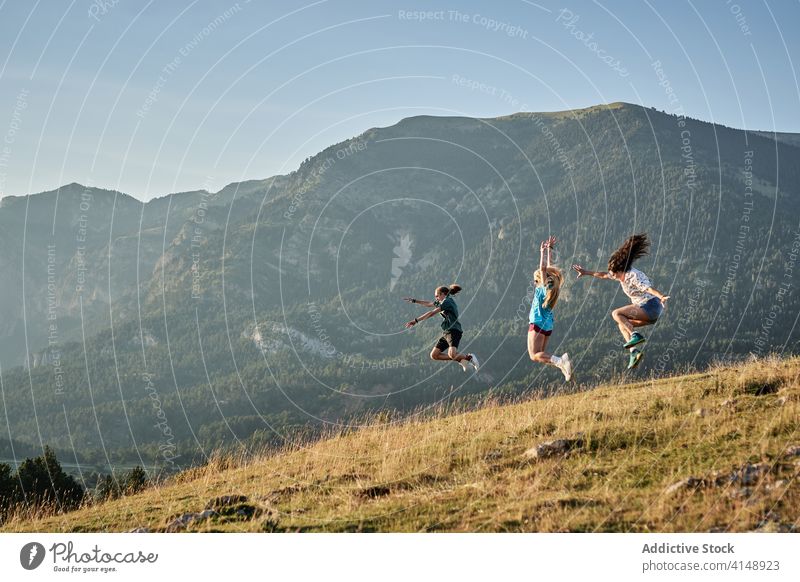 Unbekümmerte Reisende springen im Hochland genießen Freiheit sorgenfrei Reisender Sommer Urlaub Freund Menschengruppe Berge u. Gebirge Glück Moment Zusammensein