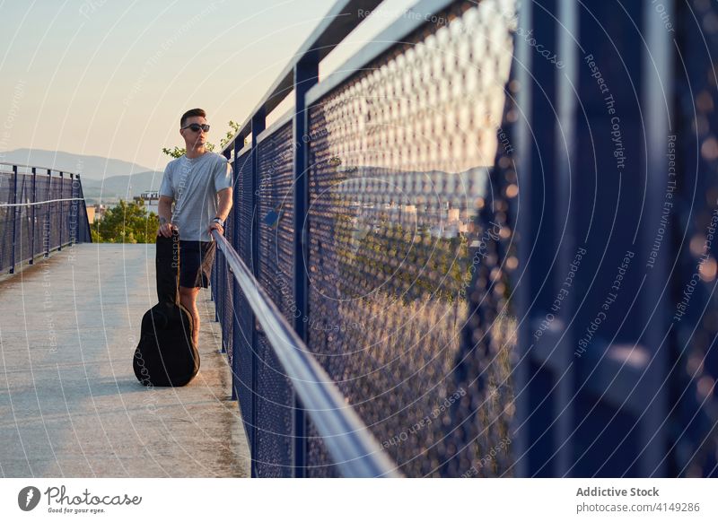 Seriöser Mann mit Gitarre in der Stadt Musiker Gitarrenspieler Großstadt Brücke Windstille ernst Talent Spieler männlich Fall selbstbewusst gutaussehend