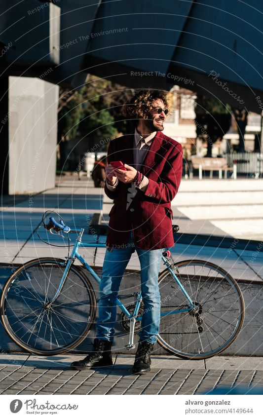 Hipster-Mann, der sein Mobiltelefon im Freien benutzt. Mobile Telefon Fahrrad Smartphone urban Großstadt Lifestyle Drahtlos Anschluss Mitteilung stylisch trendy