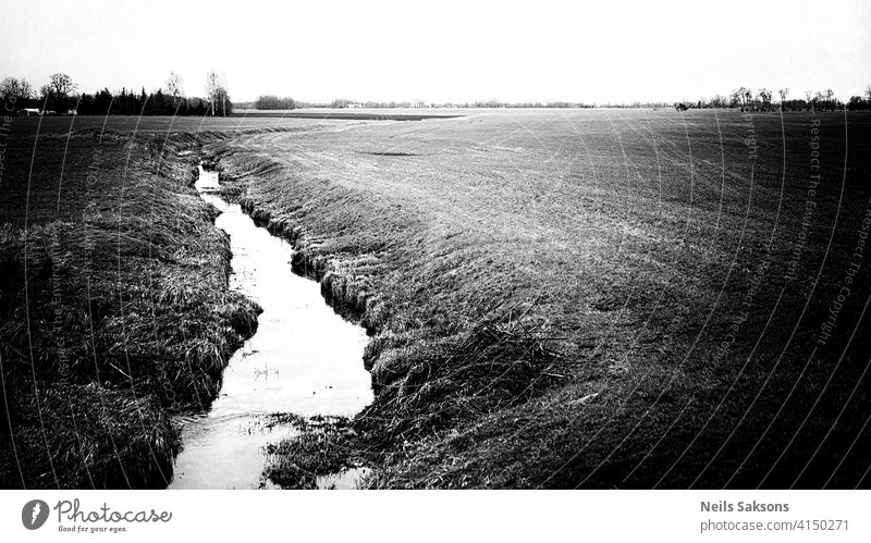 Ein kleiner Fluss, der im April durch Wiesen und landwirtschaftliche Felder fließt Athmosphäre Hintergrund schön Blues Gelassenheit Kanal Sauberkeit Cloud