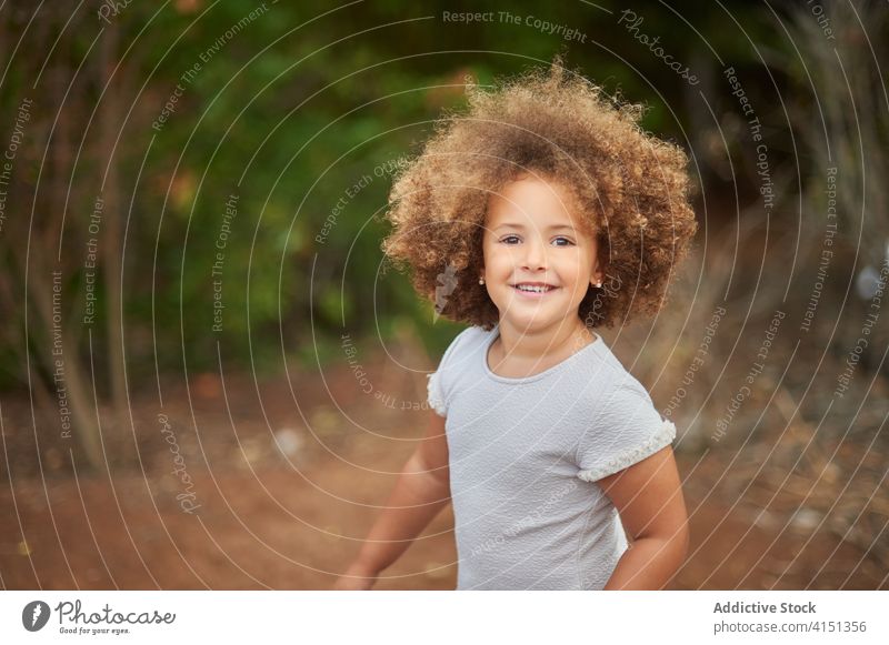 Glückliches Mädchen mit lockigem Haar im Sommerfeld krause Haare Feld heiter Kind Lächeln Porträt gemischte Rasse bezaubernd Frisur niedlich Freude Frau