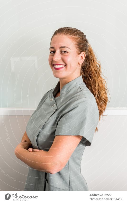 Glückliche junge Friseurin mit Blick in die Kamera Frau Salon Klinik Uniform Lächeln freundlich Personal Porträt selbstbewusst positiv Spezialist heiter Job